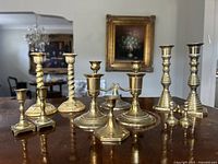Group shot showing all brass candlesticks and snuffer on tabletop