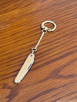 Full view of gold plated pocket cutter with keychain on wooden surface