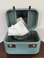 Case open showing interior mirror, elastic pocket and hotel papers