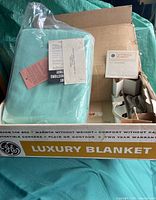 Blanket sealed in plastic, paperwork on top, controller cord visible inside original box