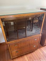 Front view showing entire two-piece cabinet with glass display section and drawer base