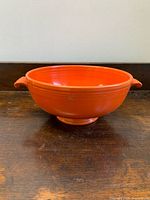 Front angled view of orange Fiesta bowl showing handles and pedestal base