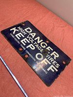 Full view of blue porcelain Danger High Voltage Hydro sign with ruler for scale