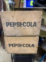 Front view showing stencilled PEPSI-COLA text on two stacked crates