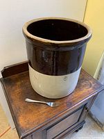 Full view of crock on small wooden table with fork for scale