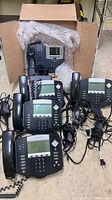 Group shot of four Polycom phones, boxed Cisco phone, cords and adapters