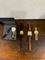 Overview of four watches and boxed pen set on tabletop