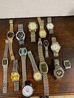 Overall view of 17 assorted wristwatches on wooden surface