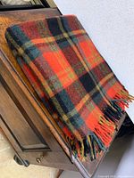 Folded tartan blanket showing plaid and fringe on furniture
