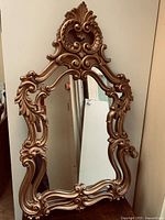 Front view of ornate gold mirror showing full frame and glass