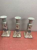 Three matching square-based ceramic candlesticks front view