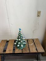 Full view of ceramic Christmas tree on bench showing cord and scale