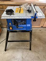 Full view of Mastercraft blue table saw on black metal stand with fence and guard