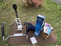 Overview of lot showing toilet safety frame, bathtub grab rail, Bristol easel box, metal detector, carry bag, tins