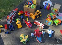 Overview of assorted toy vehicles and planes spread on pavement