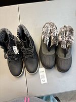 Both pairs of boots side by side on table