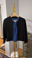Black collarless blazer with blue lining on hanger