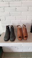 Pair of suede Chelsea boots and tan platform sandals on hearth