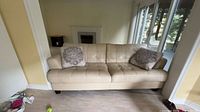 Front view of beige leather sofa with two matching throw pillows