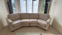 Front view of entire curved sectional showing five cream leather sections