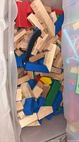 Wooden rectangular blocks with coloured ends stored in plastic bin