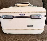 Front view of American Tourister Tapper cream vanity case showing brand badge and latches