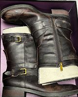 Both boots laid side by side showing leather, buckles, zippers and heels