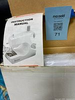 Instruction manual atop boxed sewing machine
