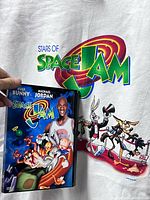 Front graphic of Space Jam shirt with DVD held over design