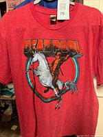 Front view of red Deadpool unicorn T-shirt on hanger