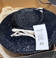 Top view of black woven dress hat with cream bows