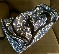 Side view of camo duffle bag showing top zipper and handles