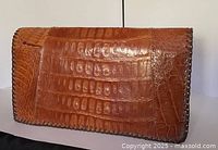 front view of tan alligator clutch showing scale pattern and whipstitched edges