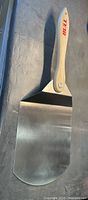 Top view of pizza peel showing stainless blade and wooden handle with Bull logo