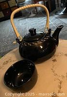 Teapot with handle and one cup on table