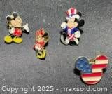 All four Disney enamel pins on dark background