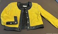 Front view of yellow and black Positano leather jacket laid flat