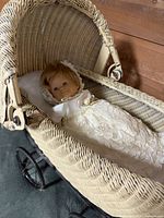 Overall view of wicker pram with doll inside