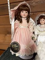 Full view of Studio Editions pink dress doll and partial adjacent doll