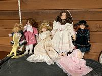 Group shot of all six porcelain dolls including rocking horse and baby doll