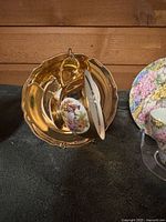 Gold-tone cup resting in matching saucer on stand
