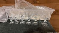 Row of six wine glasses with faceted stems in front of tote
