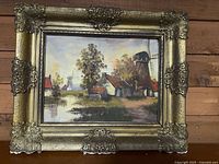 Front view of framed oil painting showing windmill scene and ornate gold-tone frame.