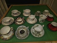 All 12 teacup and saucer sets on green surface