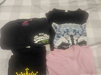 All four folded T-shirts laid out on check bedspread