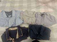 All five shirts folded, showing colors and patterns