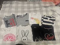 All eight folded tops laid out on check blanket