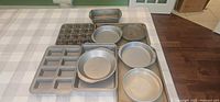 All ten pieces of mixed metal bakeware laid out on table