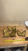 Three butterfly wall sculptures on workbench