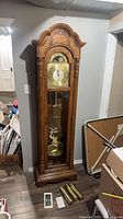 Full view of Sligh grandfather clock with accessories at base